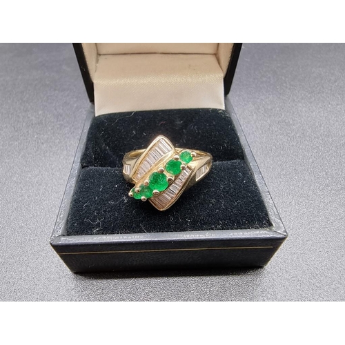 699 - An emerald and diamond crossover ring, set five graduated emeralds, stamped '14Kt', size P.... 