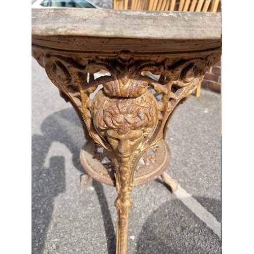 1056 - A cast iron pub table, having wooden top, 58cm wide x 70cm high.