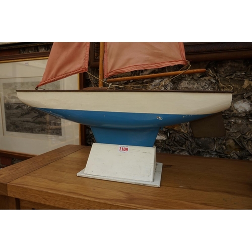 1109 - A vintage painted wood pond yacht, with brass rudder, the hull 65cm long, on stand.   ... 