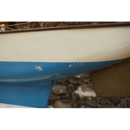 1109 - A vintage painted wood pond yacht, with brass rudder, the hull 65cm long, on stand.   ... 