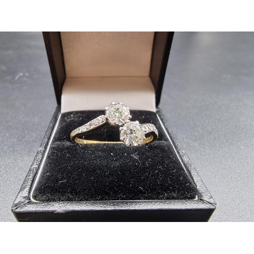 692 - A vintage yellow metal diamond crossover ring, set two diamonds of approximately 0.3ct+ each, with d... 