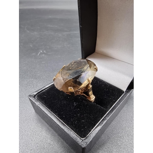 694 - A yellow metal ring, set large oval faceted smoky quartz, stamped 9ct, size K-L.