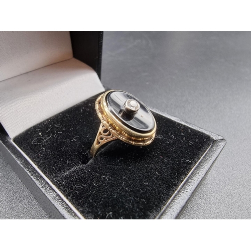 697 - A yellow metal ring, set oval black onyx with collet set diamond centre, size G 1/2.... 