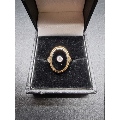 697 - A yellow metal ring, set oval black onyx with collet set diamond centre, size G 1/2.... 