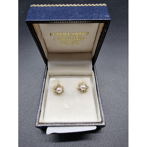 708 - A pair of 18ct gold floral ear studs, set central pearl surrounded by six diamonds, 9mm diameter, gr... 