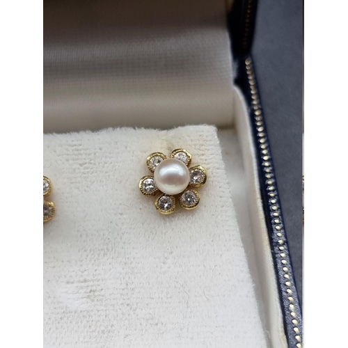 708 - A pair of 18ct gold floral ear studs, set central pearl surrounded by six diamonds, 9mm diameter, gr... 