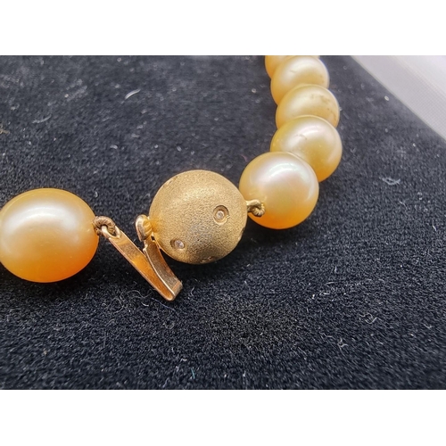 710 - A graduated South Sea pearl single strand necklace, the textured yellow metal clasp set diamonds and... 