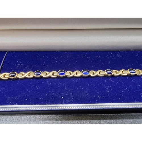 713 - A yellow metal bracelet, set eleven oval cabochon blue gemstones, stamped 14k, 18.5cm.... 