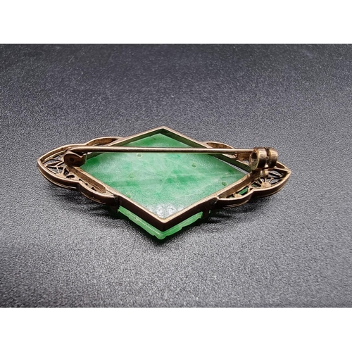 719 - A Chinese yellow metal brooch, set triangular jade plaque carved fruit, 44mm.