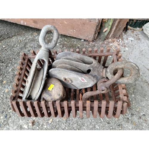 1051 - Three old winch blocks; together with a small cast iron fire grate. 