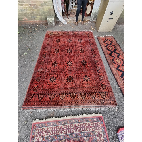 1069 - A large Bokhara rug, having repeated central field on a red ground, 286cm x 195cm, (a.f.). ... 