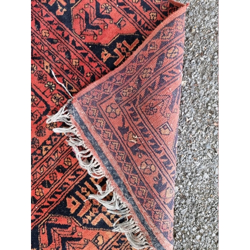 1069 - A large Bokhara rug, having repeated central field on a red ground, 286cm x 195cm, (a.f.). ... 