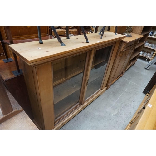 1152 - A pine bookcase, with a pair of hardwood framed glazed panel sliding doors, 142cm wide. ... 