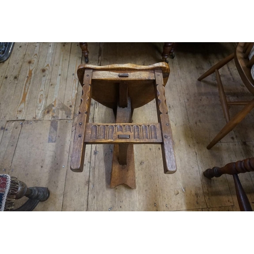 1404 - An early 20th century carved oak spinning stool, with saddle seat. 