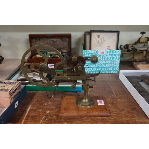 1601 - An old brass watchmaker's topping tool, on walnut plinth.   