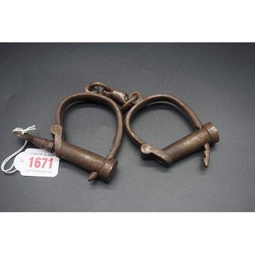 1671 - A pair of antique Hiatt steel handcuffs, with key.