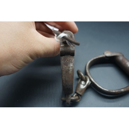 1671 - A pair of antique Hiatt steel handcuffs, with key.