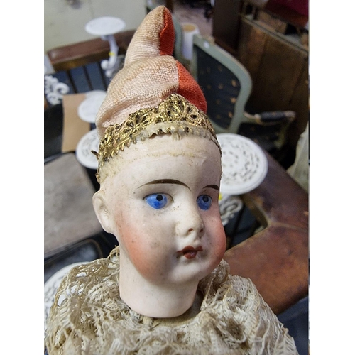 18 - An early 20th century bisque head musical rattle doll, in blue and red jester costume, head impresse... 