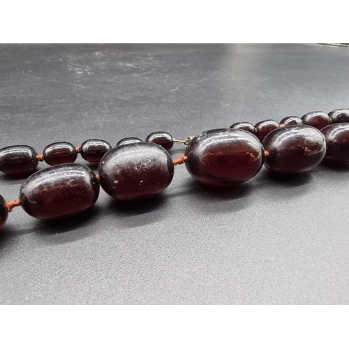 741 - A 'cherry amber' oval bead necklace, largest 30mm wide, 62cm long.