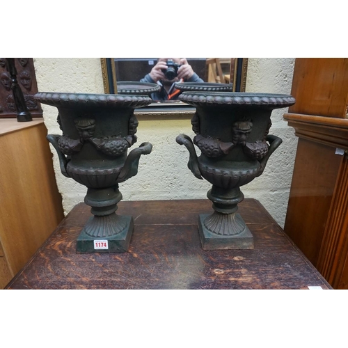 1174 - A pair of cast iron twin handled urns, 34.5cm high. 