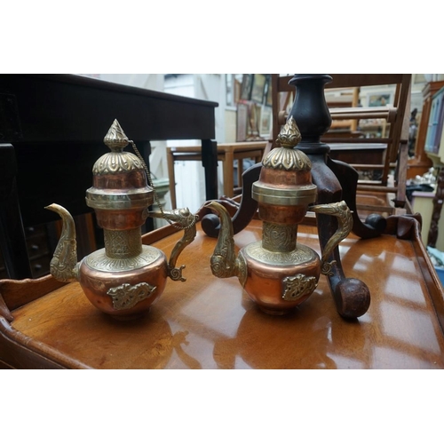 1233 - An Arabic copper coffee pot, 41cm high; together with a similar smaller pair. (3) ... 