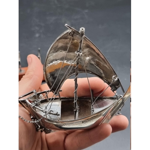 1281 - A white metal model of a dhow, on rectangular wooden base, 15.5cm high including stand.... 