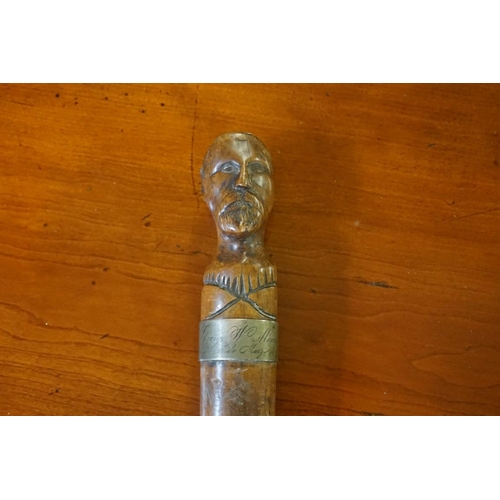 1807 - An interesting 19th century carved wood cane, with novelty portrait terminal and brass plaque i... 