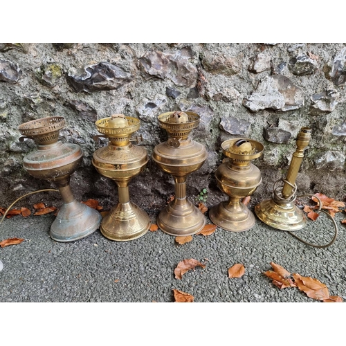 1016 - Four old oil lamps; together with a table lamp.