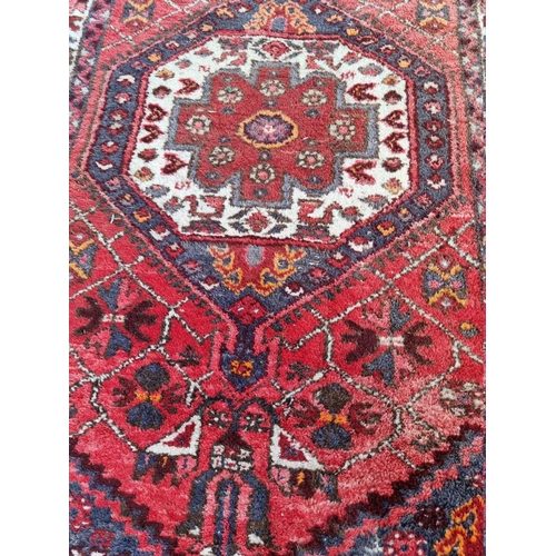 1087 - A Persian rug, having central medallion and floral borders, 191 x 102cm. 