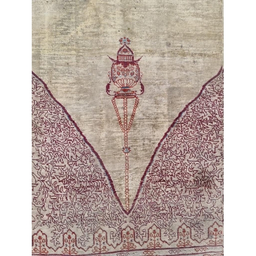 1091 - A Kashmiri silk rug, having temple design to central field, with heads to one end, with floral ... 