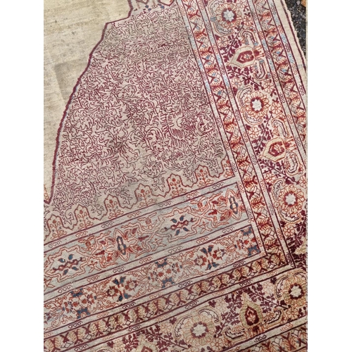 1091 - A Kashmiri silk rug, having temple design to central field, with heads to one end, with floral ... 