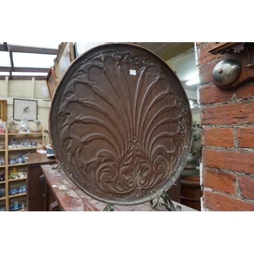 1107 - An embossed copper fire screen, 52cm diameter.