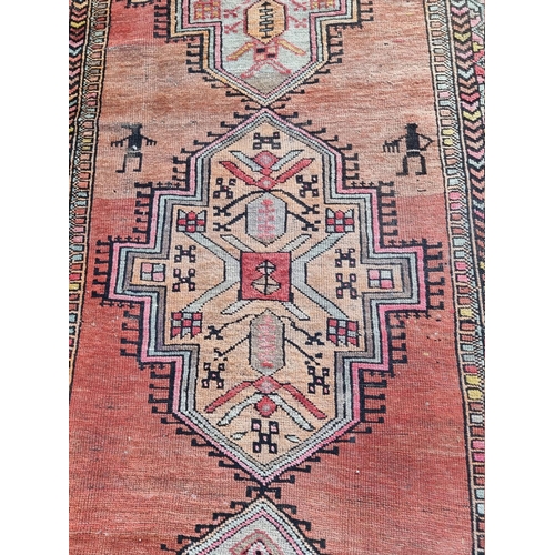 1095 - A Persian rug, having four central medallions, decorated with two small figures and geometric border... 