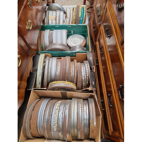 323 - FILM REELS: a large quantity of vintage film reels in metal tins, contained in 4 large boxes. (... 