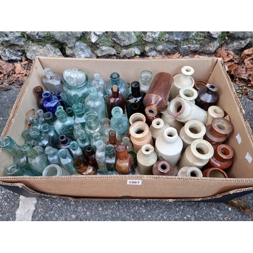 1067 - A quantity of glass and stoneware bottles. 