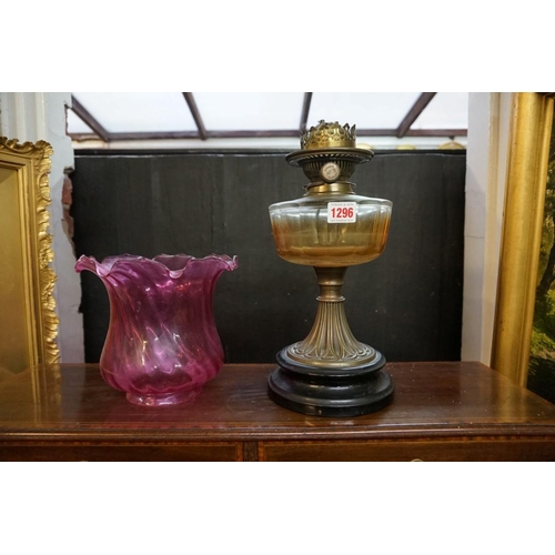 1296 - A Victorian brass oil lamp, with cranberry glass shade, height excluding chimney 48cm. ... 