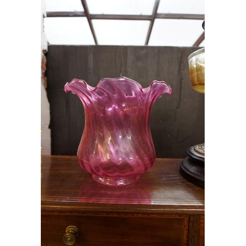 1296 - A Victorian brass oil lamp, with cranberry glass shade, height excluding chimney 48cm. ... 