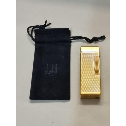 1670 - A Dunhill 'Rollagas' engine turned gilt metal lighter, with velvet drawstring bag.