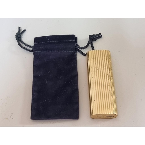 1671 - A Cartier gilt metal lighter, (dents), with velvet drawstring bag.