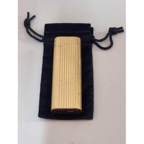 1671 - A Cartier gilt metal lighter, (dents), with velvet drawstring bag.