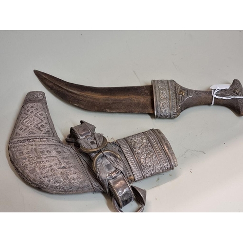 1713 - An Omani white metal mounted jambiya and sheath, with horn handle.