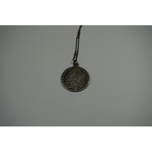 417 - Coins: a George III 1787 silver shilling, with attached pendant loop and chain.