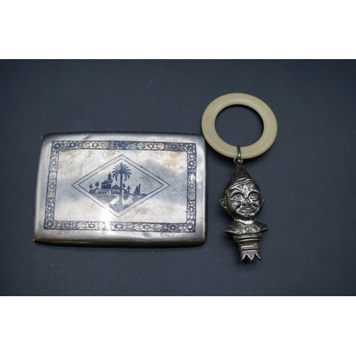 606 - An Egyptian niello cigarette case, 11.5cm; together with a child's silver teether. (2)... 