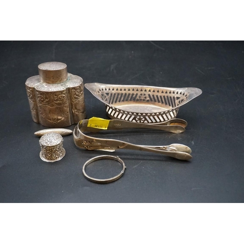 629 - A group of silver items, to include: a tea caddy; two pairs of sugar tongs; a pierced oval bonbon di... 