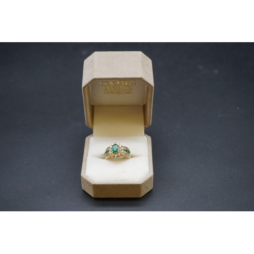 671 - A yellow metal emerald and diamond cluster ring, set central oval emerald surrounded by twelve brill... 