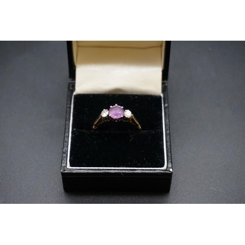 676 - A yellow metal three stone amethyst and diamond ring, set central amethyst approx 0.75ct with two di... 