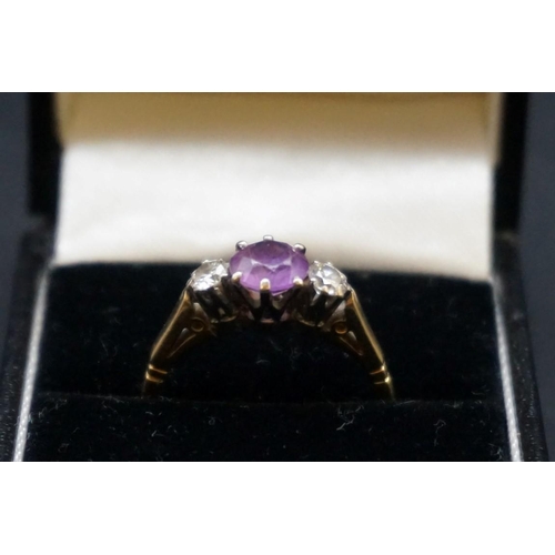 676 - A yellow metal three stone amethyst and diamond ring, set central amethyst approx 0.75ct with two di... 