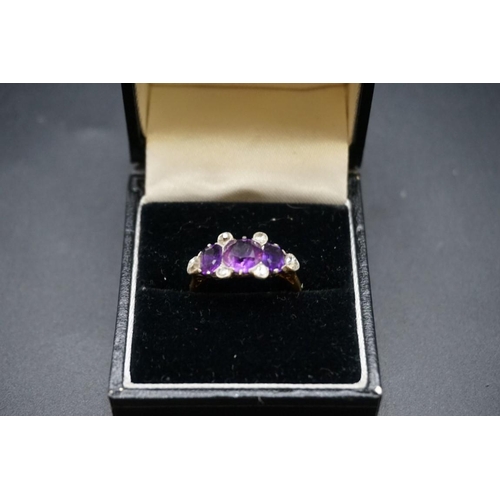 699 - A yellow metal ring set three amethysts and six diamonds, stamped Plat 18ct, size N.... 