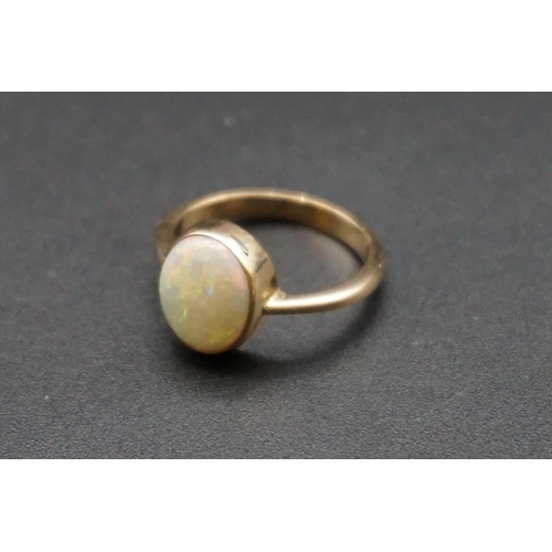 706 - A yellow metal ring set oval cabochon opal, size N.