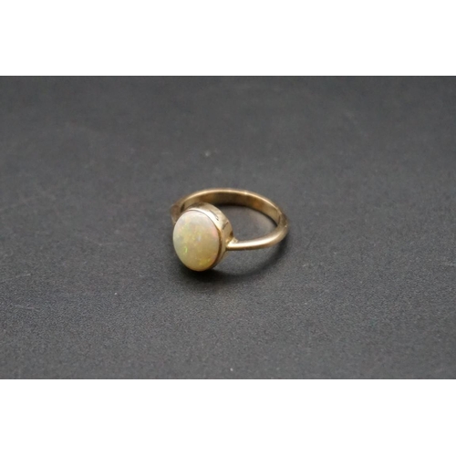 706 - A yellow metal ring set oval cabochon opal, size N.